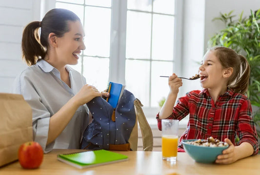 School-age child eating a healthy breakfast with fruit cereal and milk before school